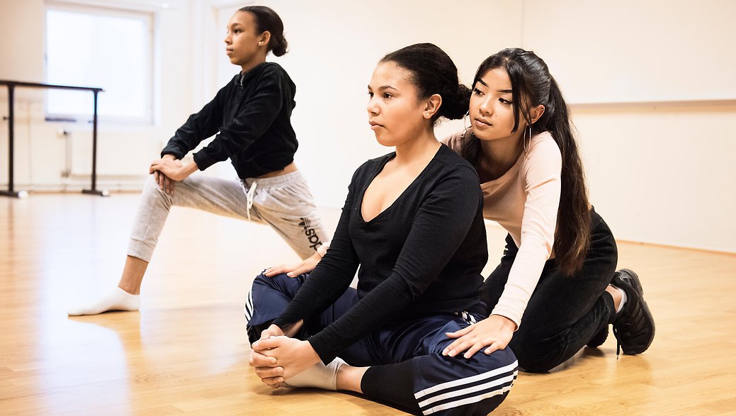 Dans är en av alla passioner man kan ägna sig åt på Fryshuset, här ser du tre unga tjejer som stretchar efter att de dansat tillsammans.