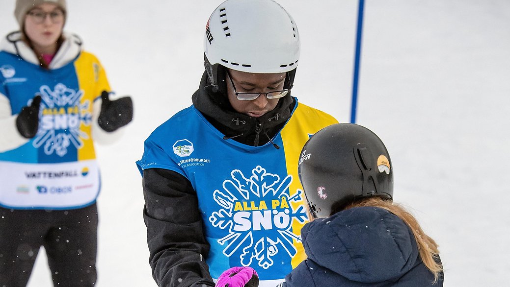 Ahmed på bilden har sedan han kom till Sverige funnit snöglädjen och hjälper till att sprida den till andra. Här lär han en flicka åka skidor.
