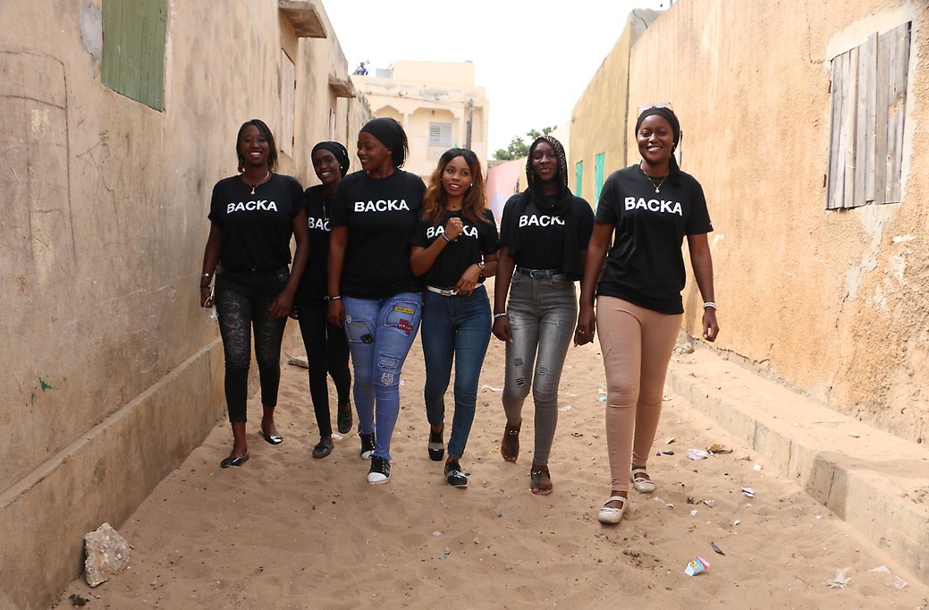 Tjejer från BACKA projektet samlade i Senegal. De är glada och går längs en gata i Senegal.
