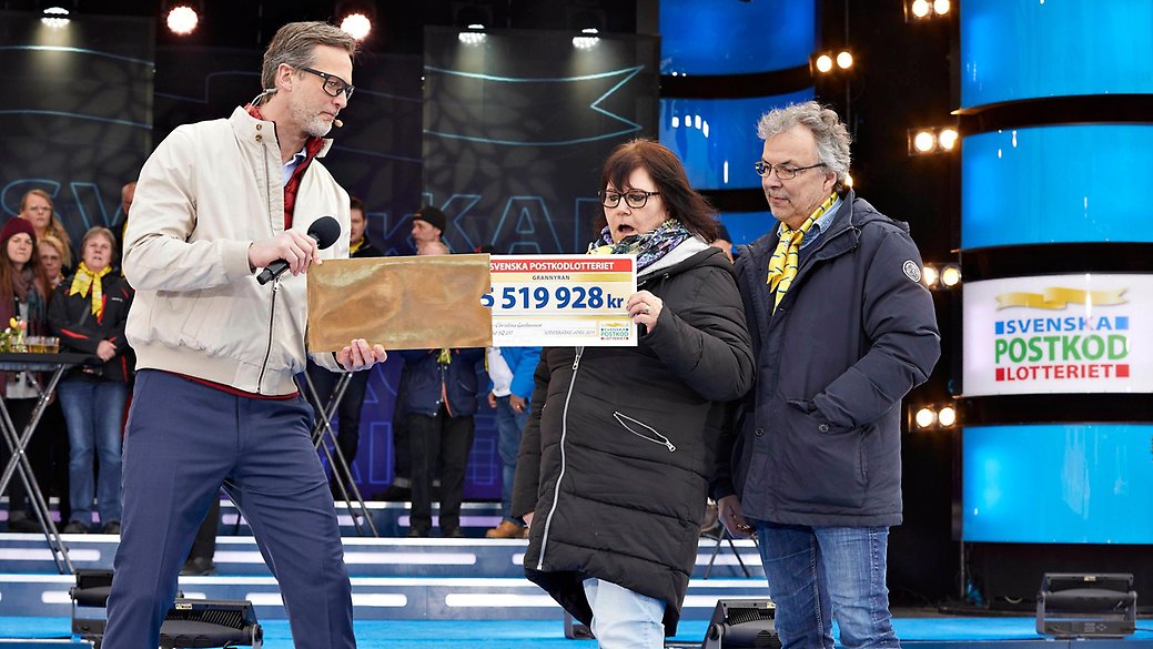 Ann-Christina står på scenen under Grannyran i Söderbärke och tar emot sin vinstcheck på 5 miljoner kronor